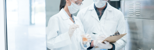 Two brunette scientists in lab with white coats